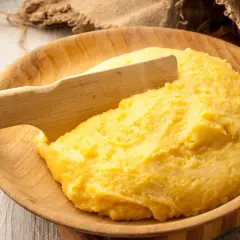 Gorąca polenta, czyli co to jest? Aromatyczna, żółta kaszka kukurydziana podana w drewnianej misie, gotowa do jedzenia.