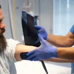 Medyk w niebieskich rękawiczkach zakłada mankiet na ramię pacjenta. Badanie może pomóc ocenić poziom lipoproteiny, co to jest i jak wpływa na zdrowie.