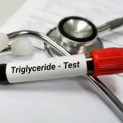 Probówka z krwią do badania trójglicerydów leży na stetoskopie. Wysokie trójglicerydy mogą wpływać na samopoczucie.