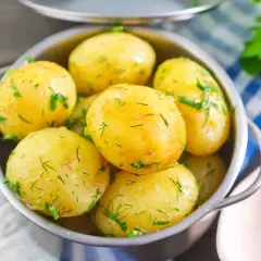 Młode ziemniaki, okraszone świeżym koperkiem, kuszą apetycznym wyglądem w metalowej miseczce. Idealne na letni obiad!
