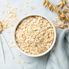 Misternie ułożone płatki owsiane w misce i na łyżce. Czy płatki owsiane mają gluten? Zwykłe płatki owsiane nie zawierają glutenu, ale mogą być zanieczyszczone podczas przetwarzania.
