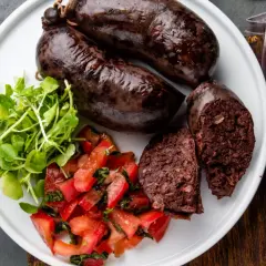 Kaszanka na talerzu z pomidorami i rukolą. Zastanawiasz się nad kaszanka kcal? To sycące danie.
