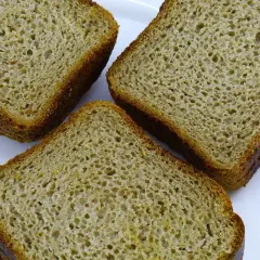 Trzy kromki chleba orkiszowego na białym talerzu. Czy mąka orkiszowa ma gluten? Tak, orkisz zawiera gluten.