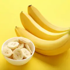 Kilka żółtych bananów i miseczka pokrojonych plasterków. Czy banan jest lekkostrawny? Tak, jest to owoc łatwo przyswajalny.