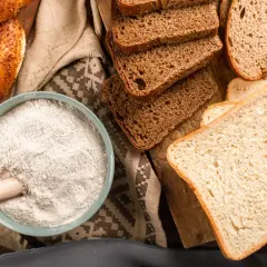 Mąka, chleb i bajgiel – oto główne źródła, w czym jest gluten. Składniki do wypieku na drewnianej desce.