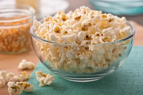 Chrupiąca góra popcornu w szklanej misce. Czy popcorn jest zdrowy? Zależy od dodatków!