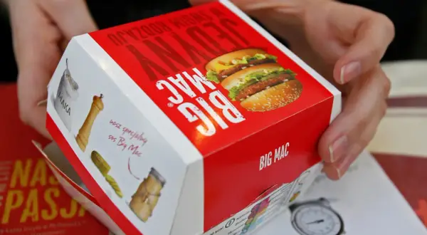 Ręce trzymają pudełko Big Maca z informacją o jego zawartości, w tym mcchicken kcal.