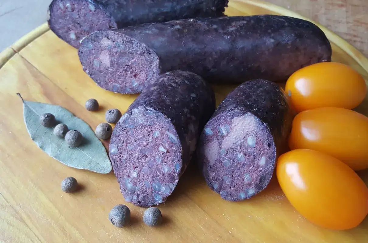 Kaszanka na desce z przyprawami i pomidorami. Zastanawiasz się nad kaszanka kcal?