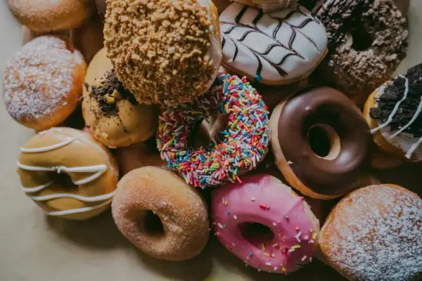 Kolorowe pączki z posypką, lukrem i cukrem pudrem. Każdy kusi swoim wyglądem, a ich pączek kcal może przyprawić o zawrót głowy.