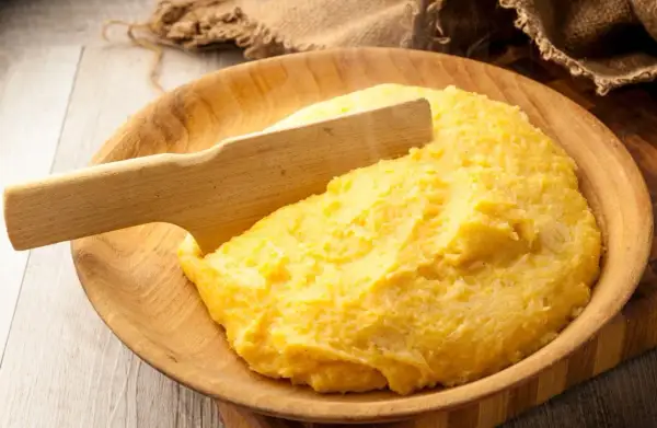 Gorąca polenta, czyli co to jest? Aromatyczna, żółta kaszka kukurydziana podana w drewnianej misie, gotowa do jedzenia.