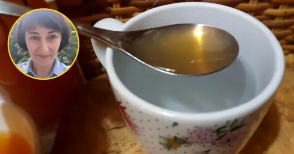 Kobieta z uśmiechem na twarzy pokazuje łyżkę z wodą z octem jabłkowym, gotową do wypicia.