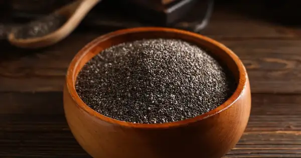 Nasiona chia jak jeść? W drewnianej misce pełnej drobnych, czarnych ziarenek. Idealne do dodania do jogurtu, owsianki czy smoothie.